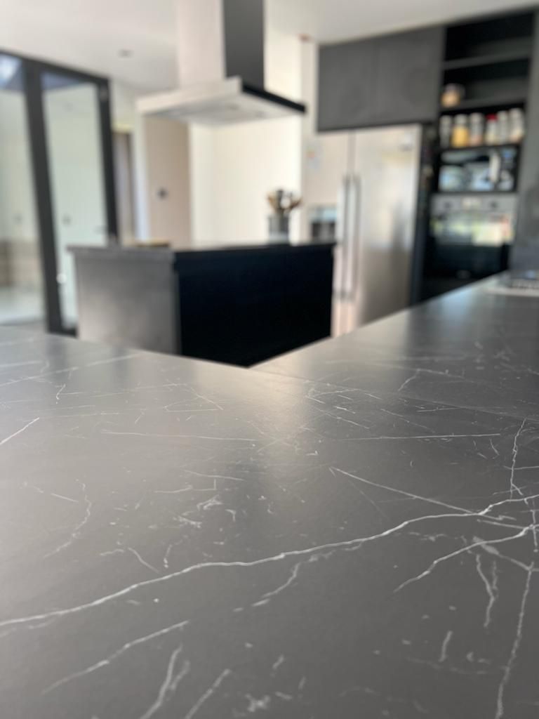 Primer plano de una encimera oscura con vetas blancas en una cocina moderna