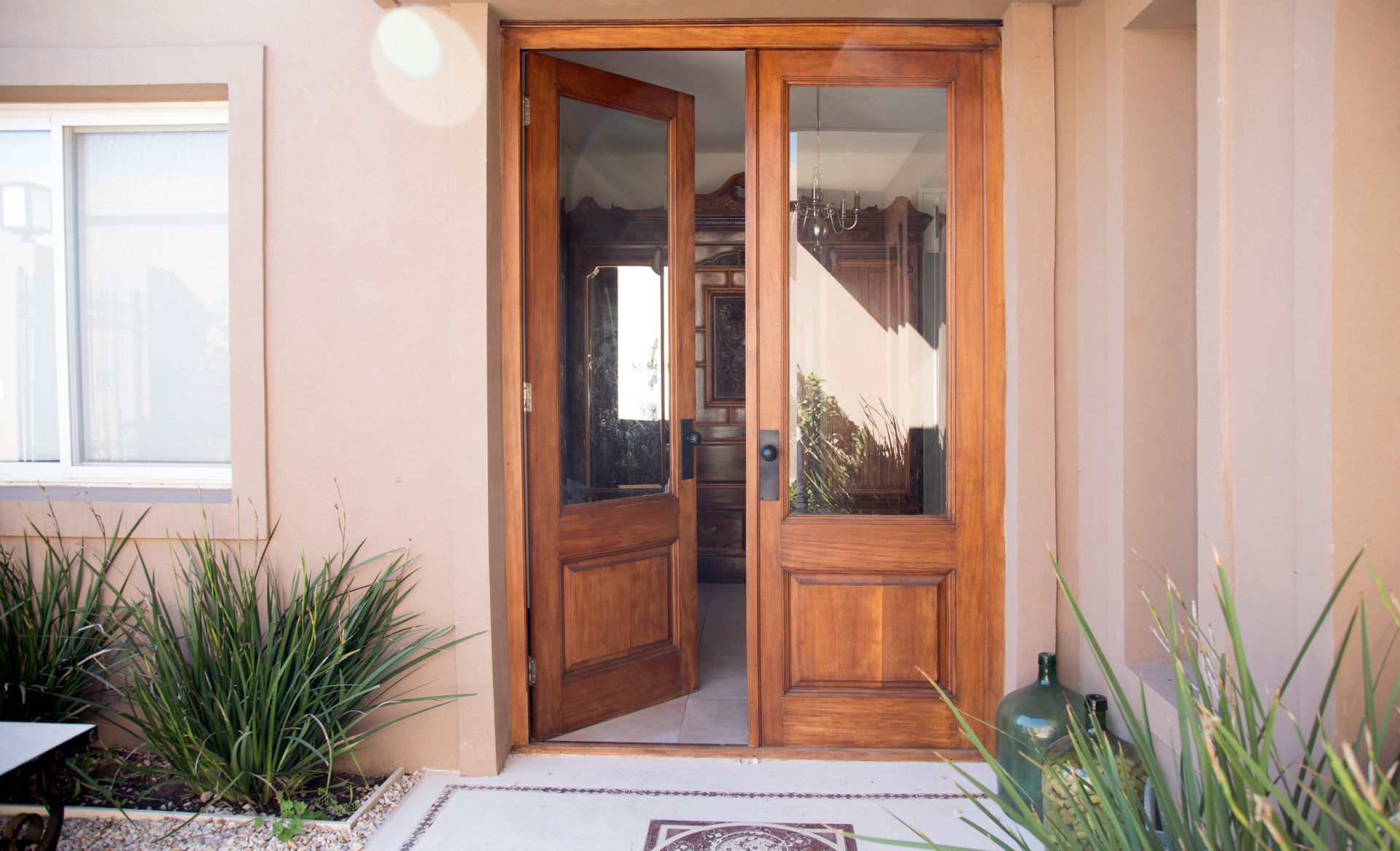 Puertas dobles de madera, una entreabierta, que dan acceso a una vivienda.