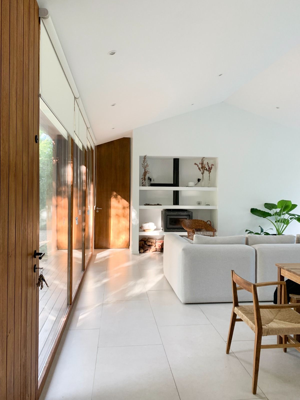 Salón luminoso y moderno con puerta de madera y paredes blancas, que incluye un sofá seccional y estanterías empotradas.