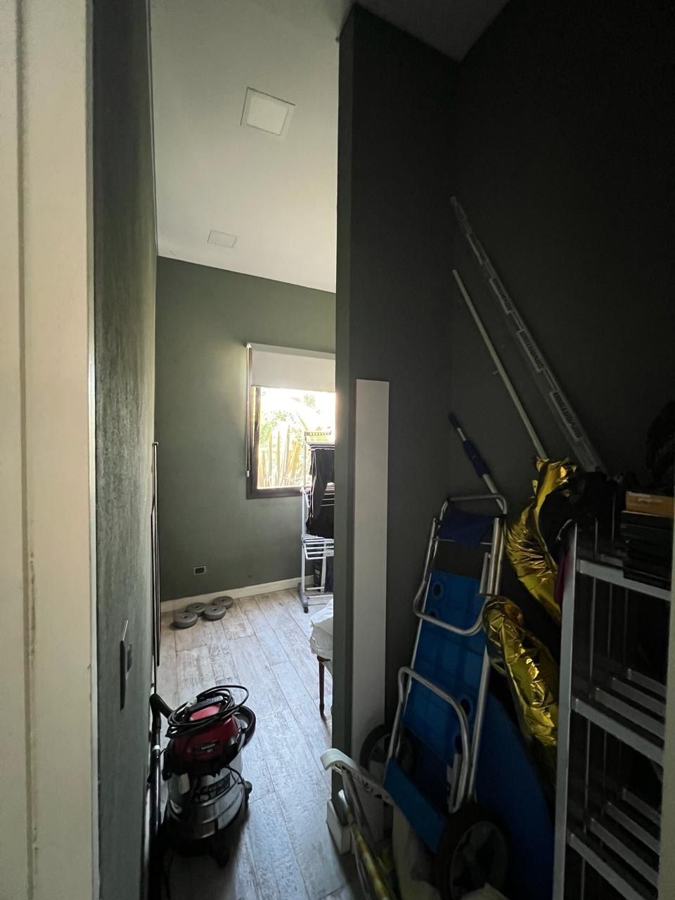 Pasillo estrecho que conduce a una habitación con ventana. 