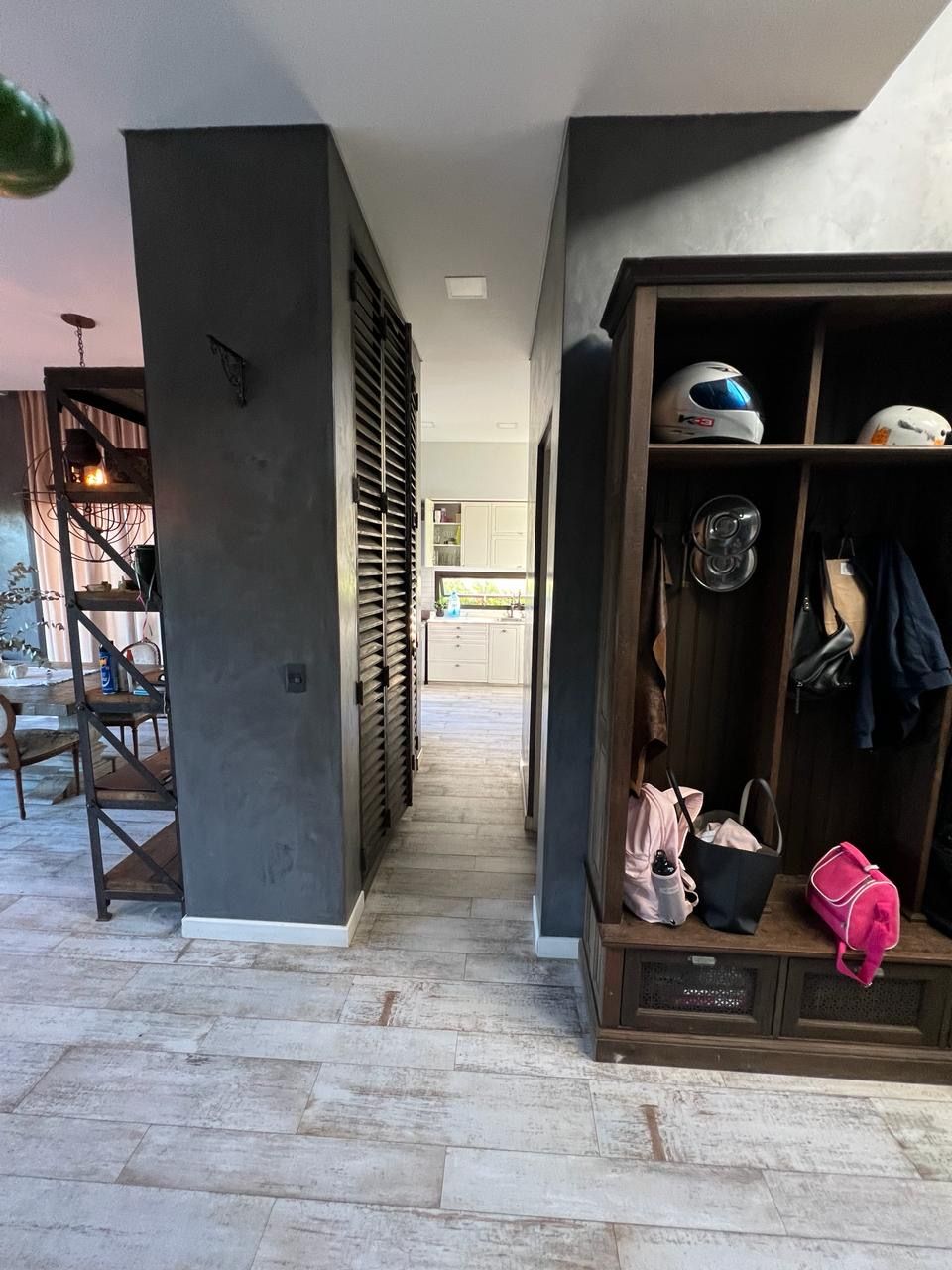 Recibidor con paredes de color gris oscuro, armario de madera y pasillo que conduce a la cocina.