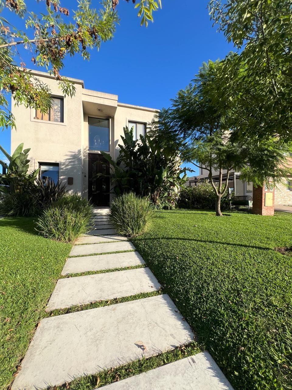 Una casa de dos plantas con fachada de estuco y un camino de hormigón que conduce a la puerta principal. 