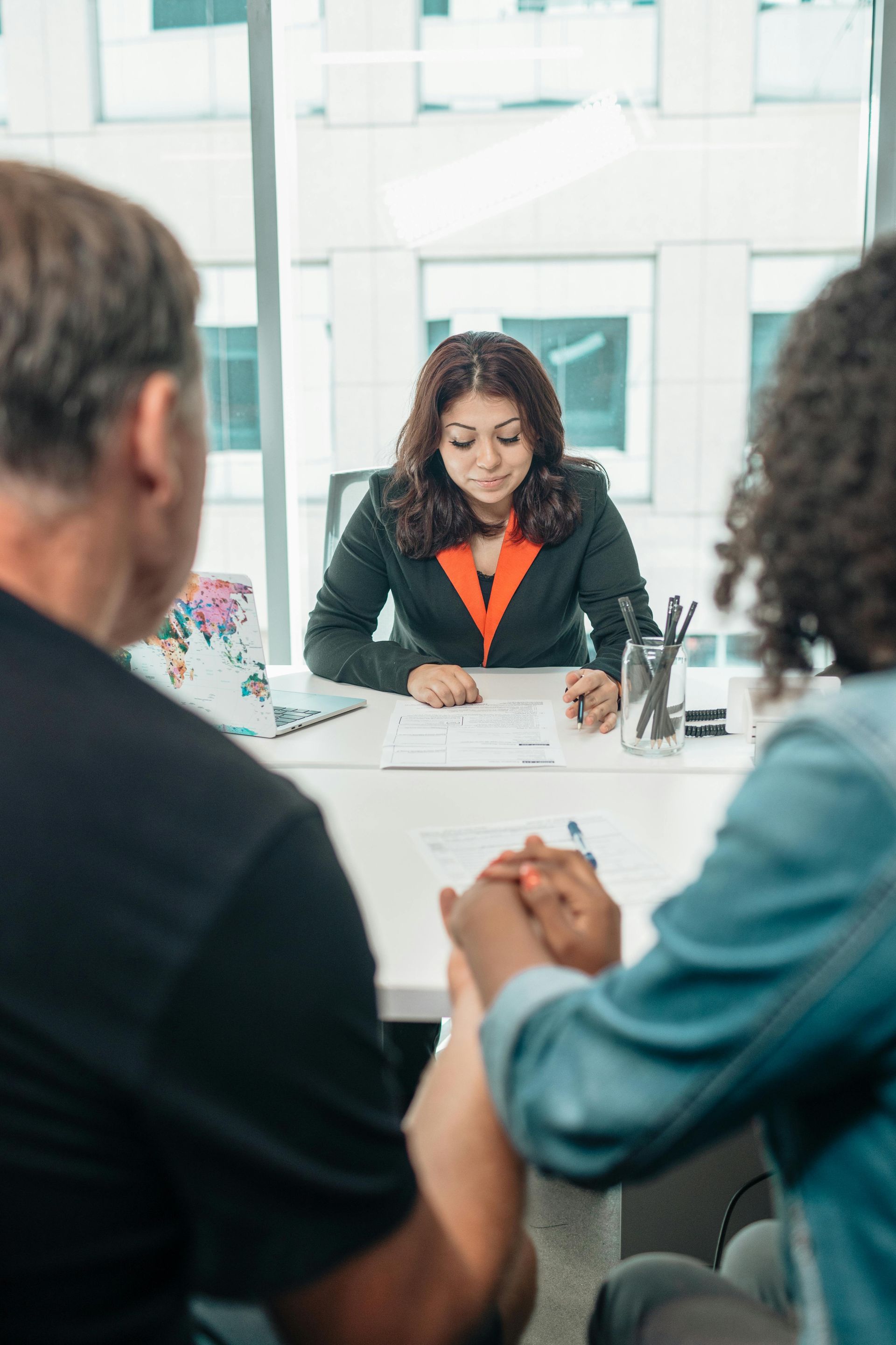 Female mediator meeting with two parents in a modern office to discuss parenting plan arrangements.