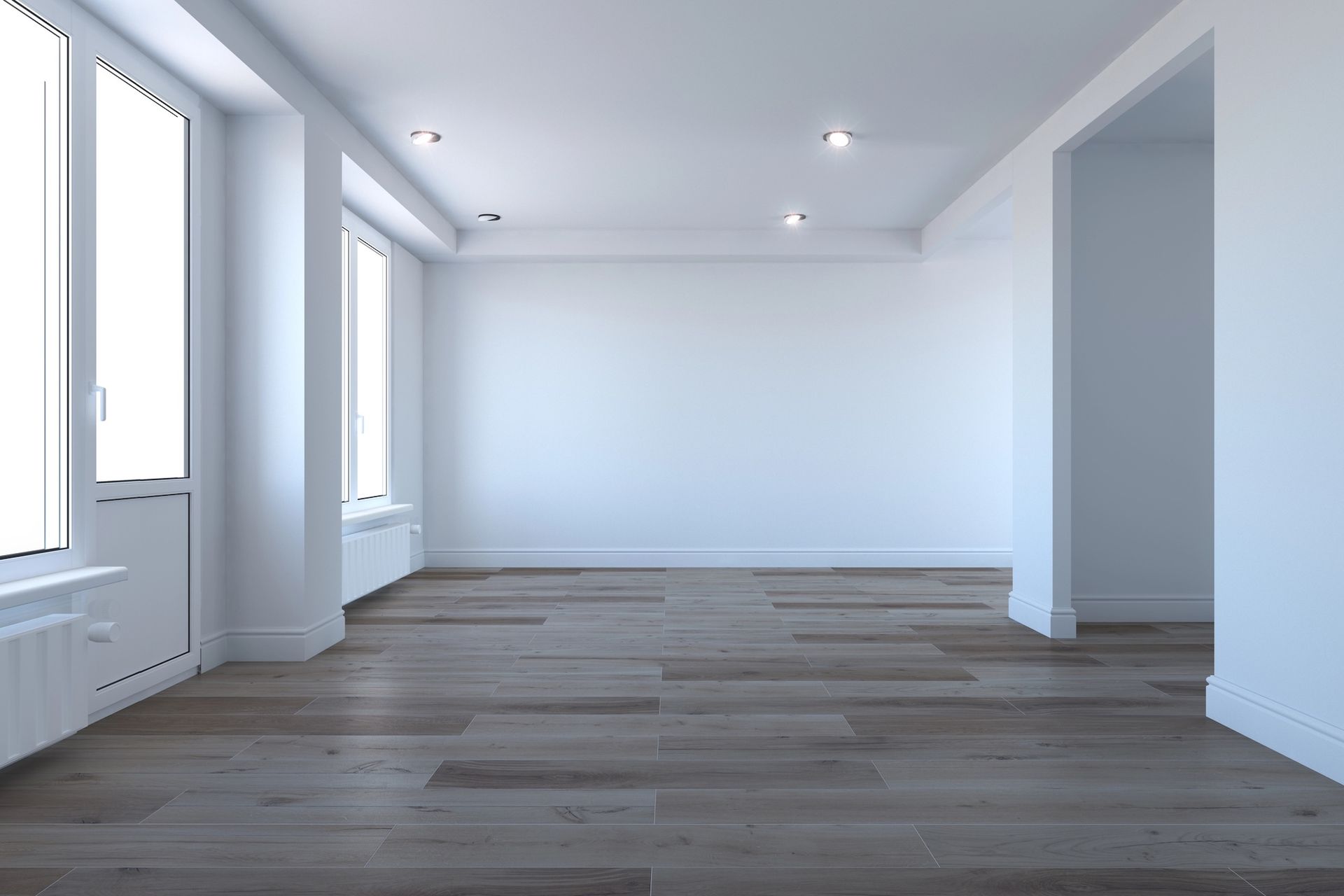 Empty room with wood floor, white walls, windows, and recessed lights.