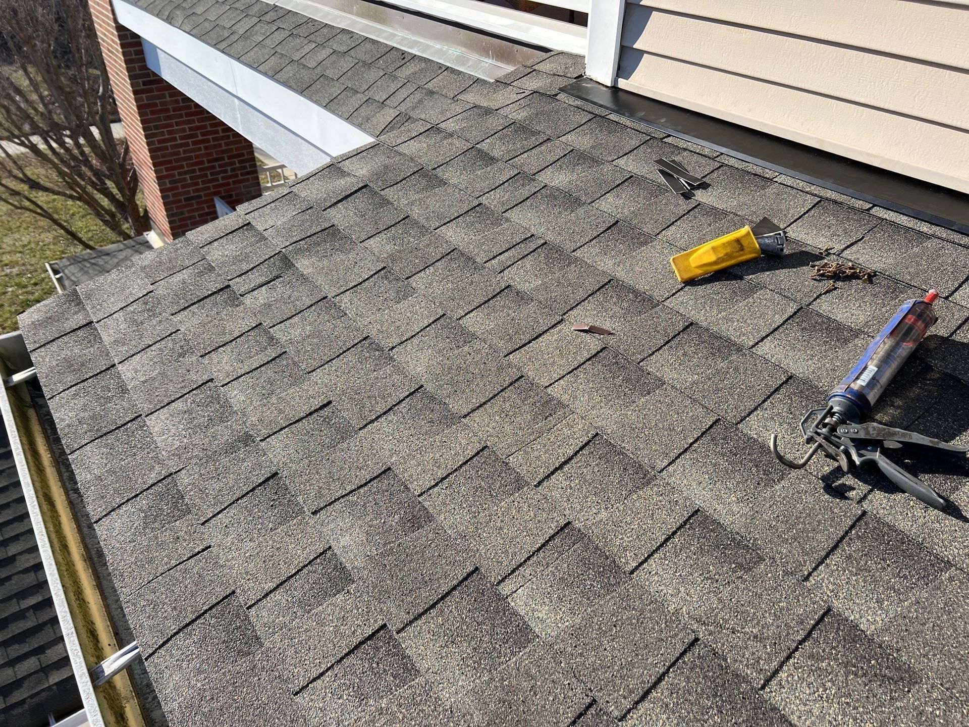 Roof shingles being repaired with tools on a residential house rooftop
