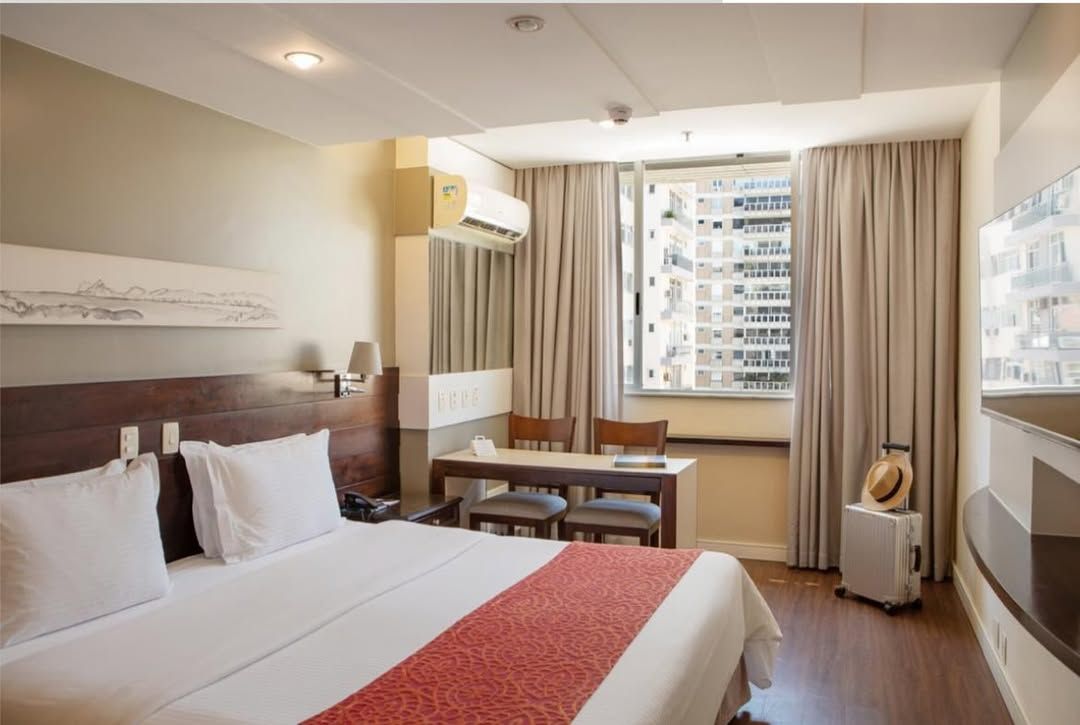 Um quarto de hotel com uma cama king size e uma escrivaninha. Sol de Ipanema Hotel