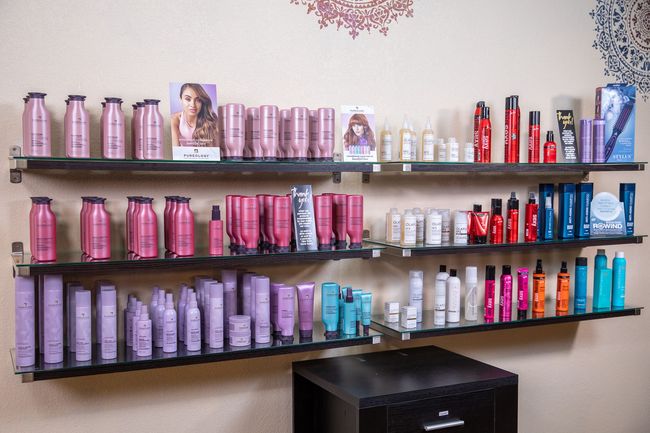 Shelves of various hair care products in a salon; pink, purple, red, and blue bottles.