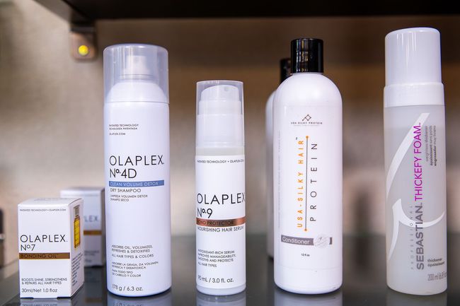 Shelf with Olaplex and other hair care products in white bottles.