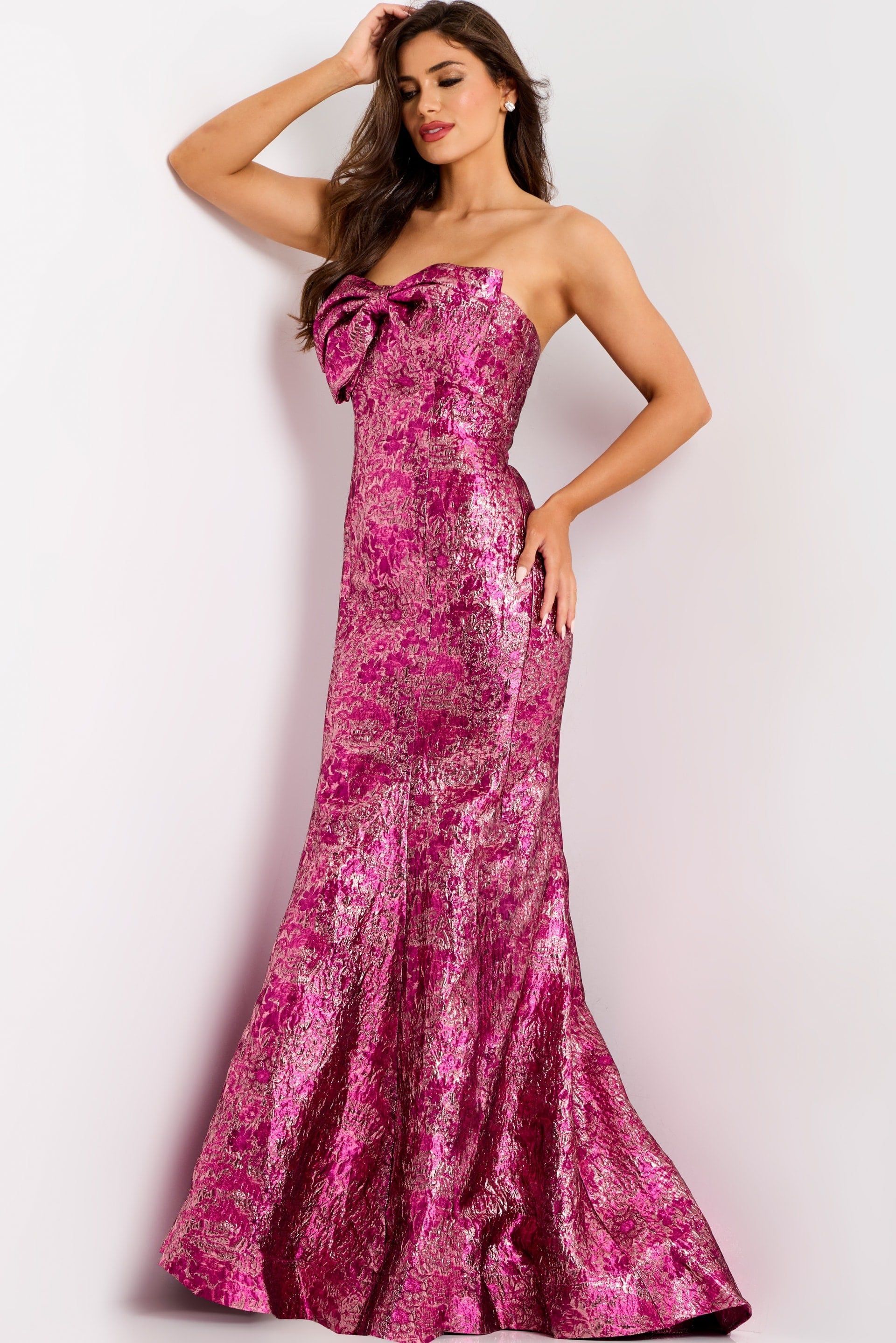 Woman in a sequined magenta strapless gown poses against a white backdrop.