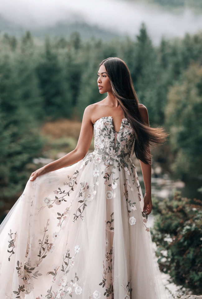 Woman in a white wedding dress twirling on a stone patio with a European-style building in the background.