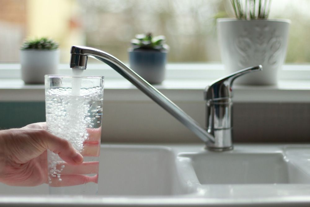 A Person is Filling a Glass of Water From a Faucet — Hinterland Water Cartage in Mooloolah Valley, QLD