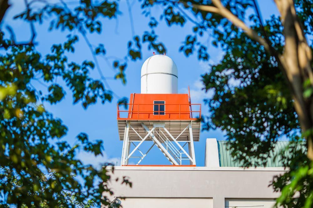 A White and Orange Tower on Top of a Building Surrounded by Trees — Hinterland Water Cartage in Mooloolah Valley, QLD