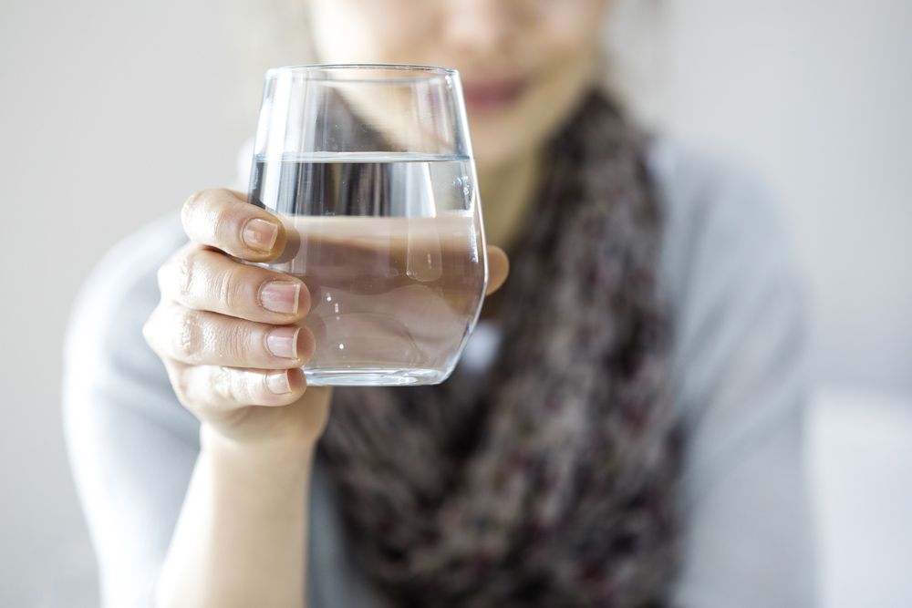 A Woman is Holding a Glass of Water in Her Hand — Hinterland Water Cartage in Mooloolah Valley, QLD