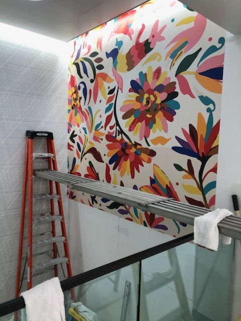 A colorful floral mural is being painted on a wall