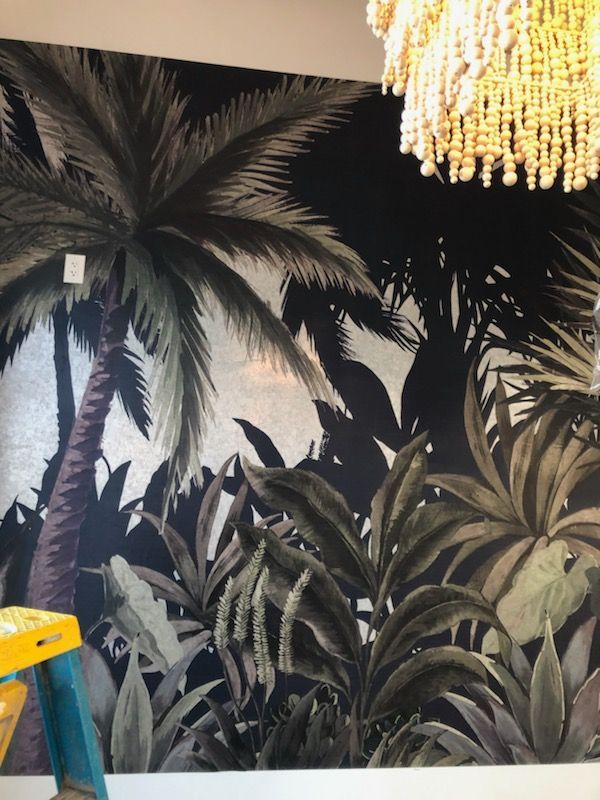 A wall with a painting of palm trees and leaves on it