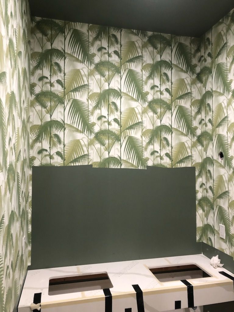 A room with a green wall and a tropical wallpaper.