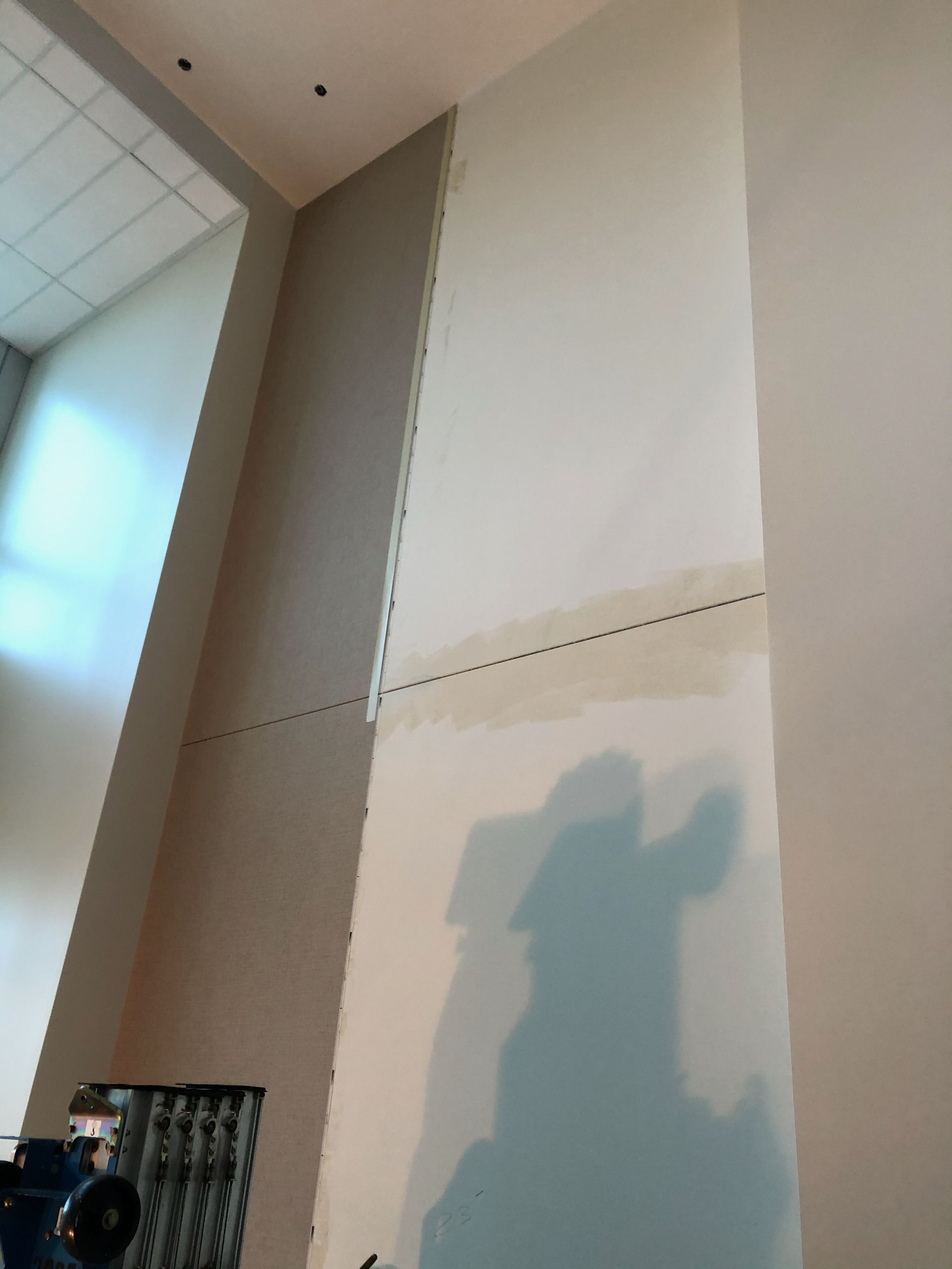 A shadow of a person is cast on a white wall