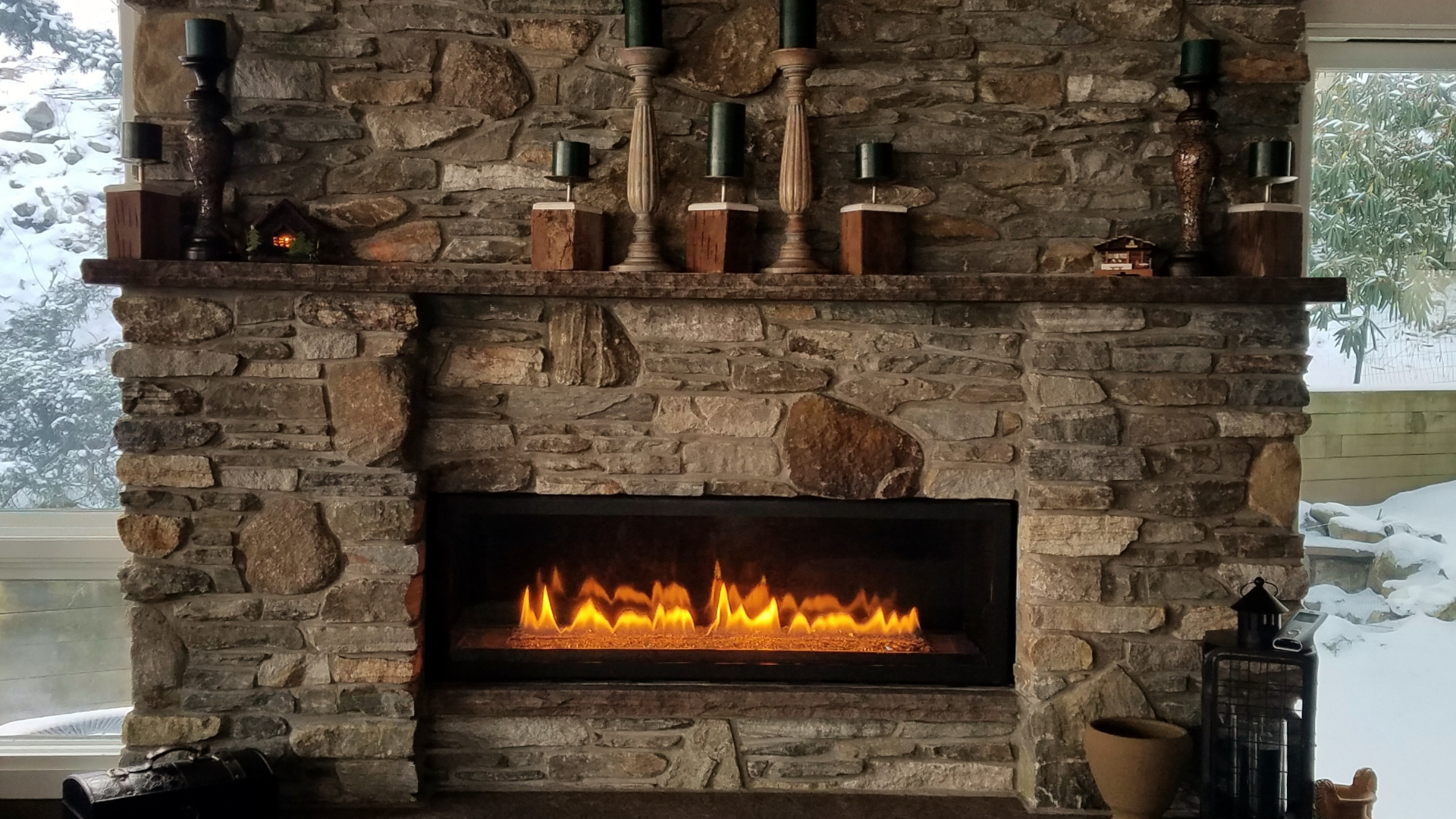 A large stone fireplace with candles on the mantle