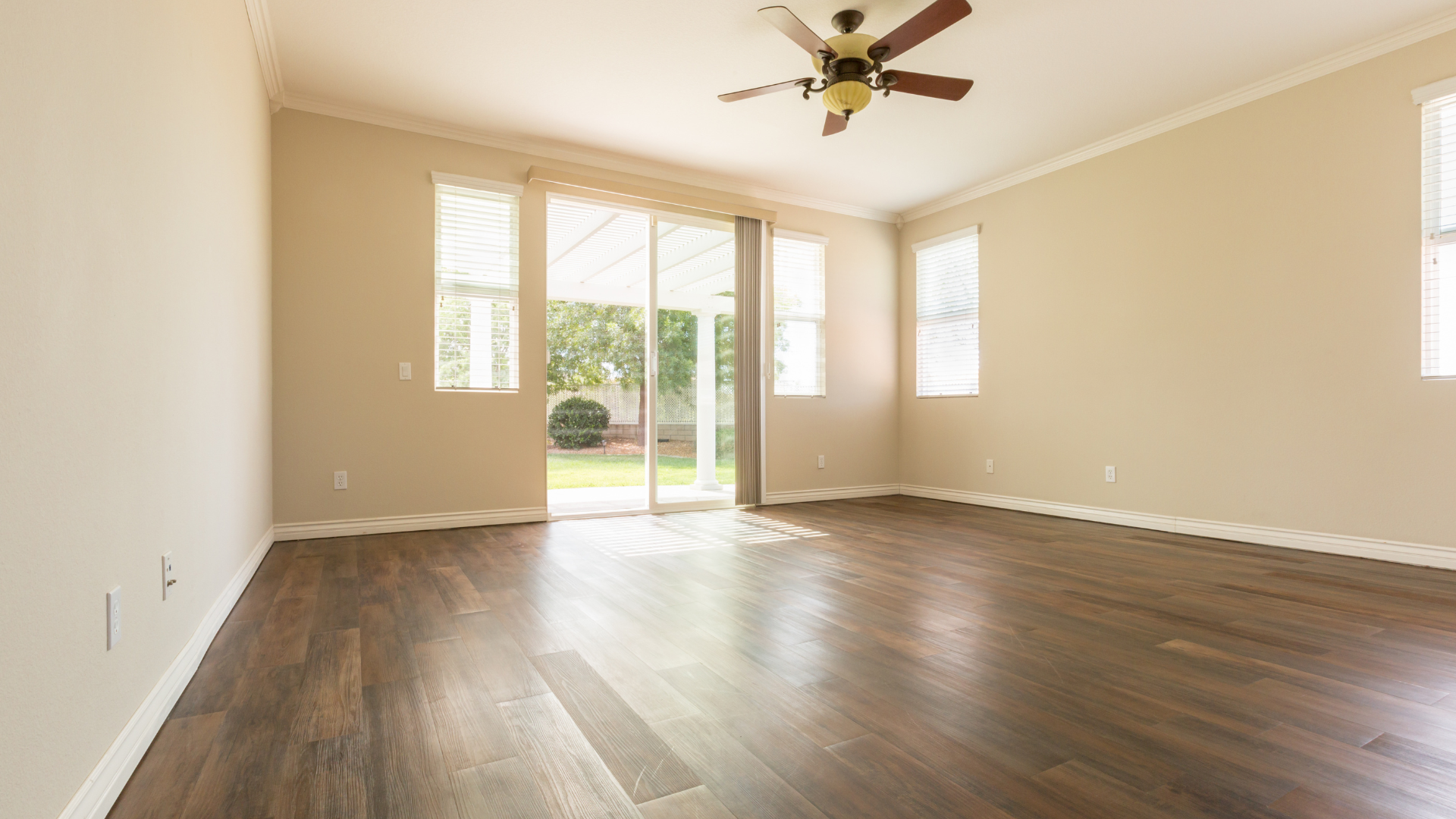 An empty living room with hardwood floors and a ceiling fan.