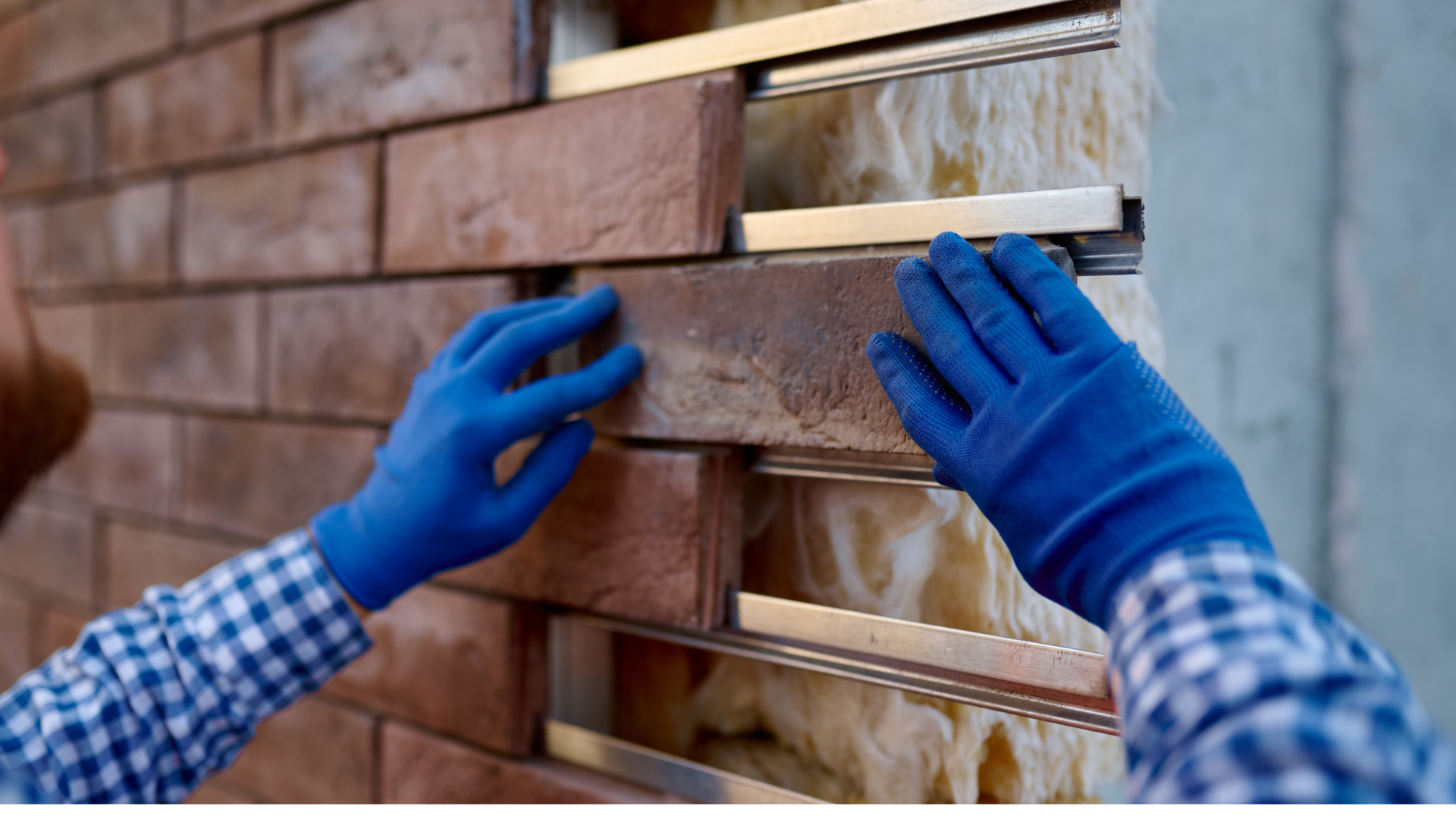 A man wearing blue gloves is installing bricks on a wall.