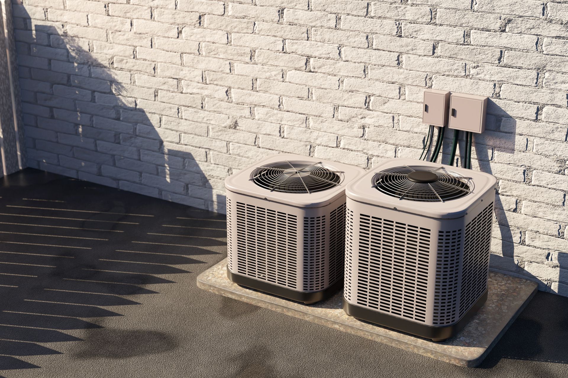 Two outdoor air conditioning units beside a white brick wall in sunlight
