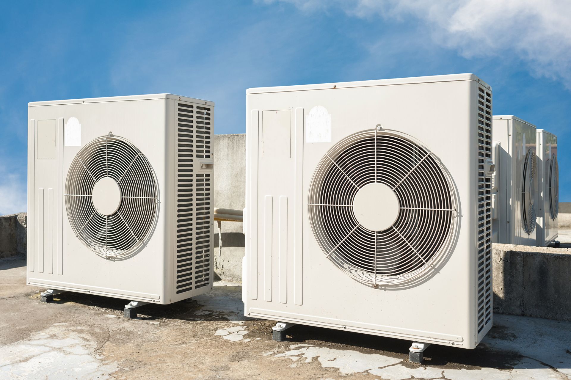 Large white industrial air-conditioning units outdoors under a blue sky
