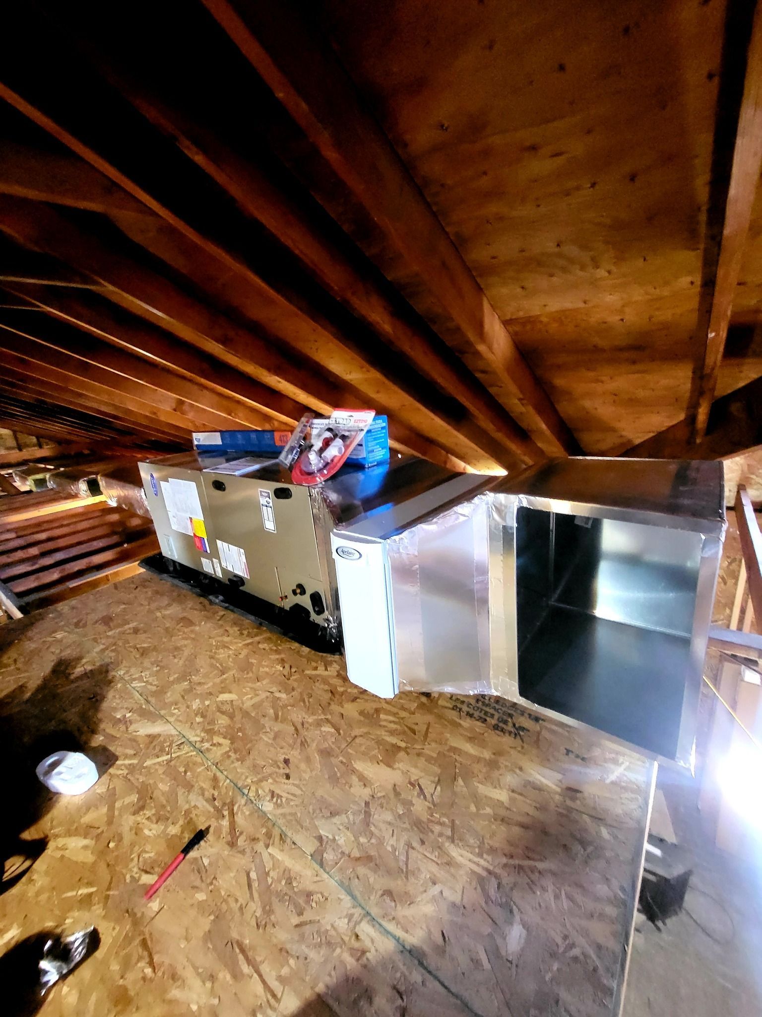 An air conditioner is being installed in the attic of a house.