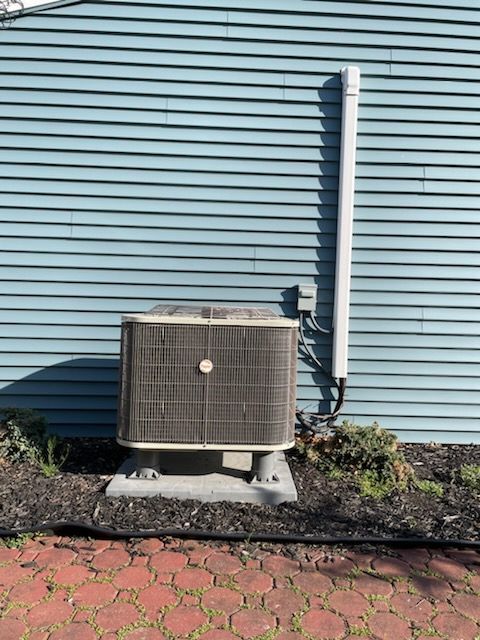 An air conditioner is sitting on the side of a house.