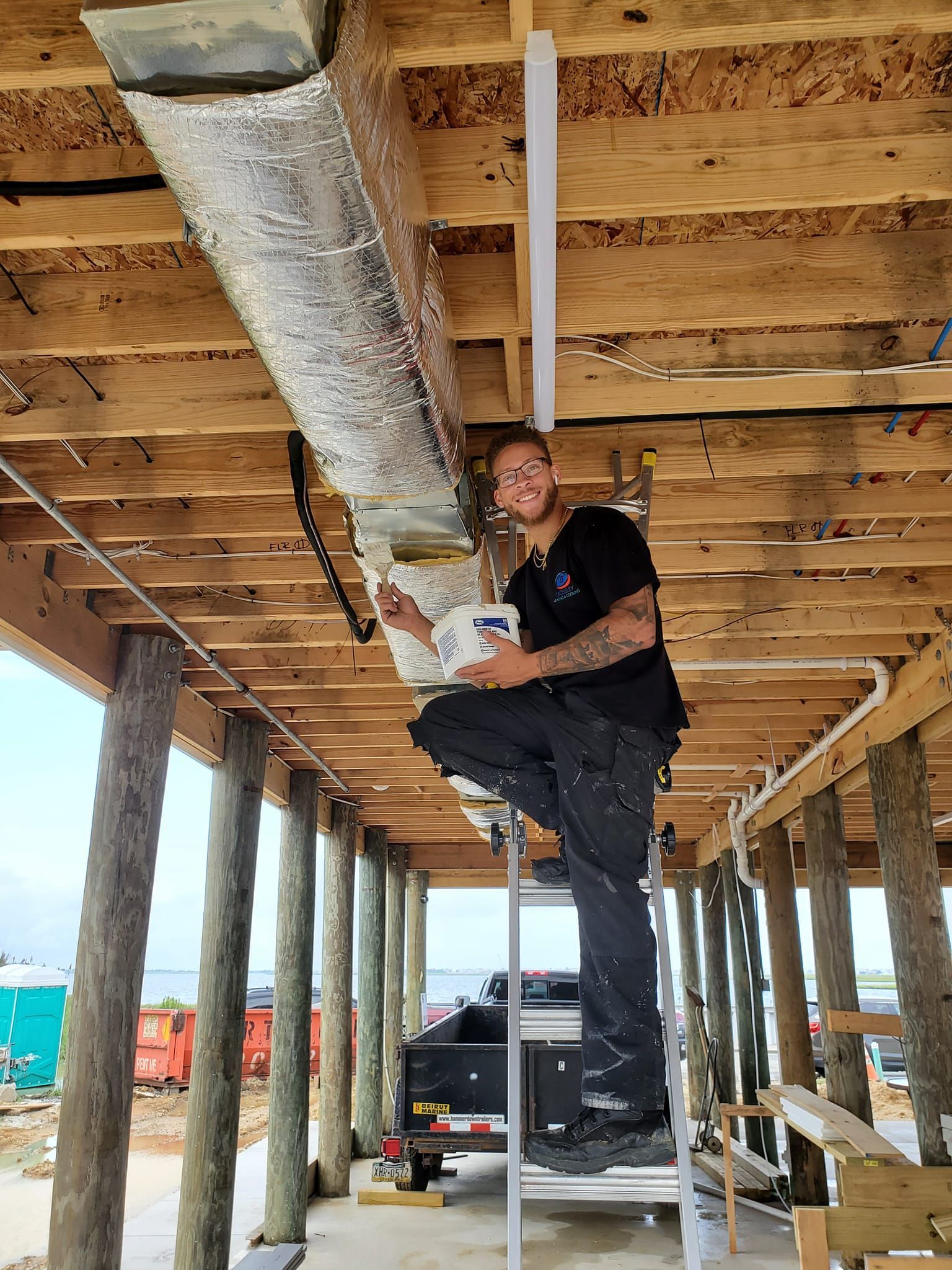 A man is sitting on a ladder under a wooden structure.