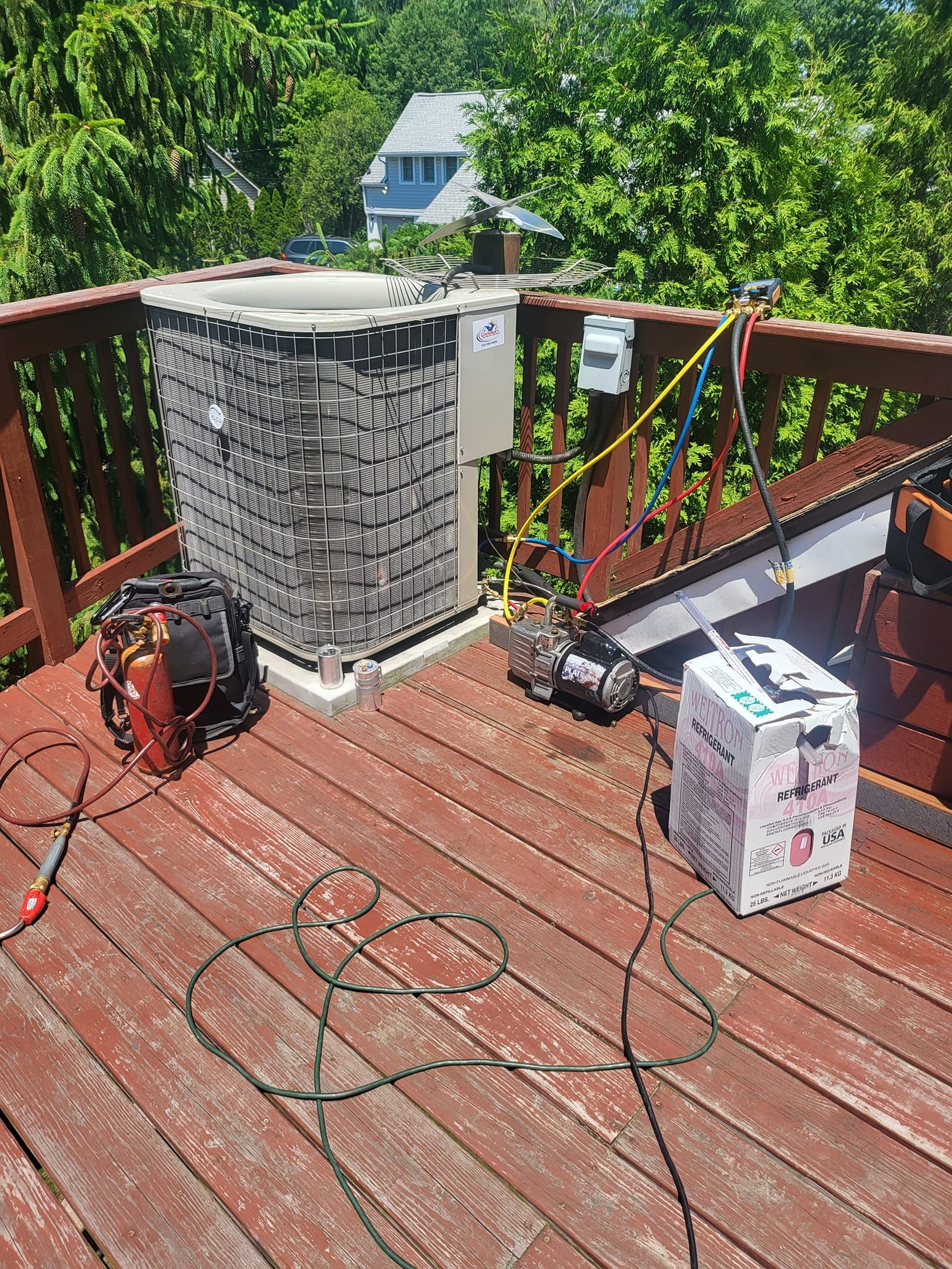 An air conditioner is being repaired on a wooden deck.