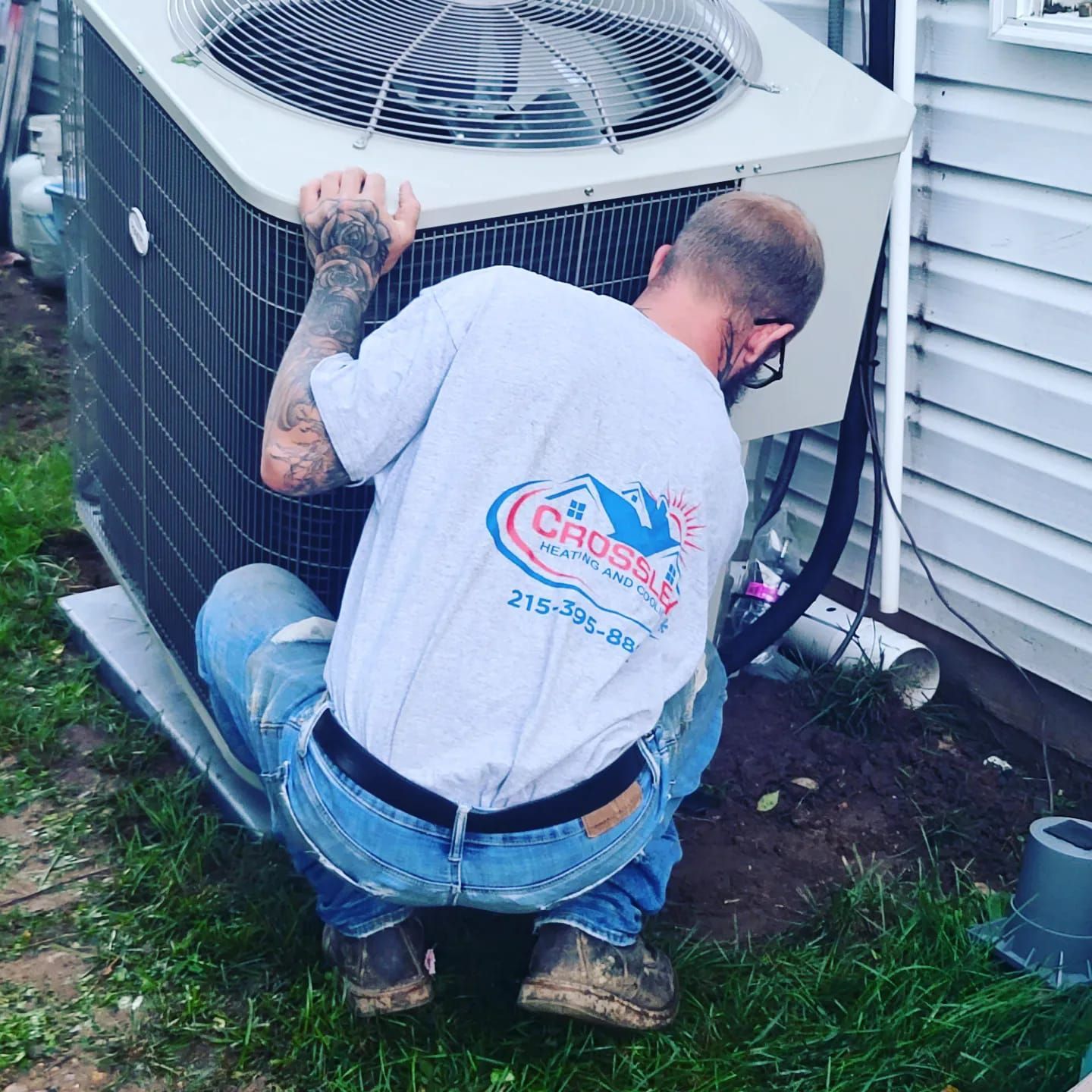 A man is working on an air conditioner outside of a house.