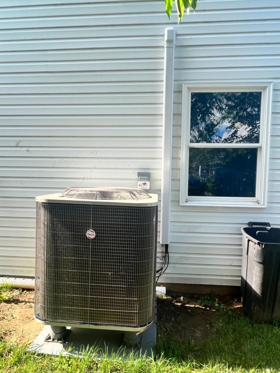 An air conditioner is sitting on the side of a house next to a window.