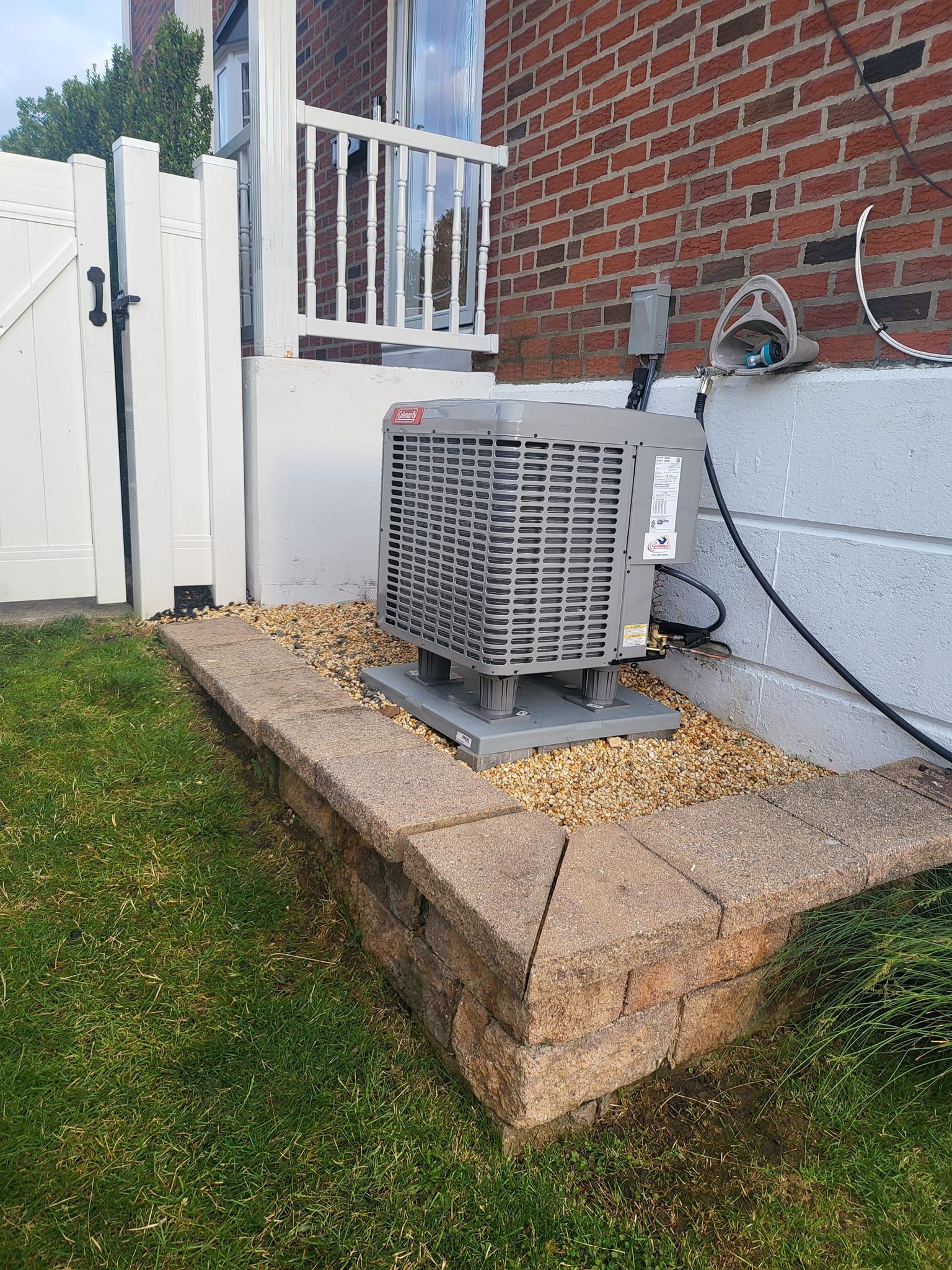 An air conditioner is sitting on the side of a brick building.