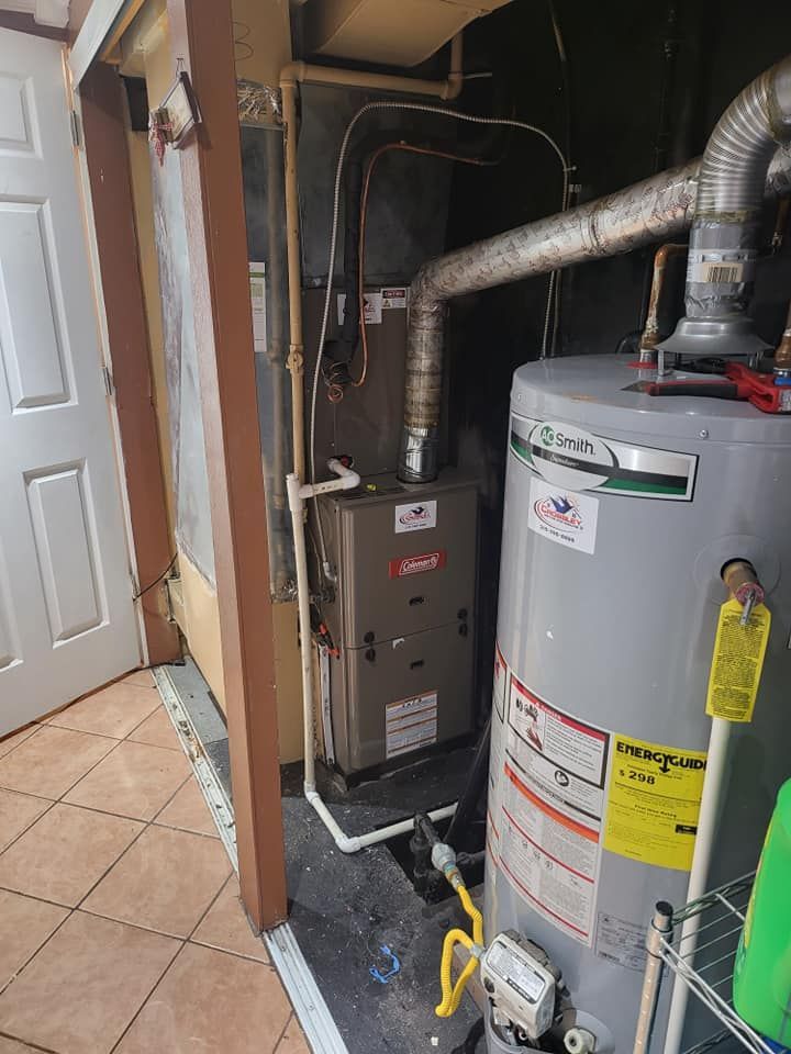 A water heater is sitting next to a furnace in a room.