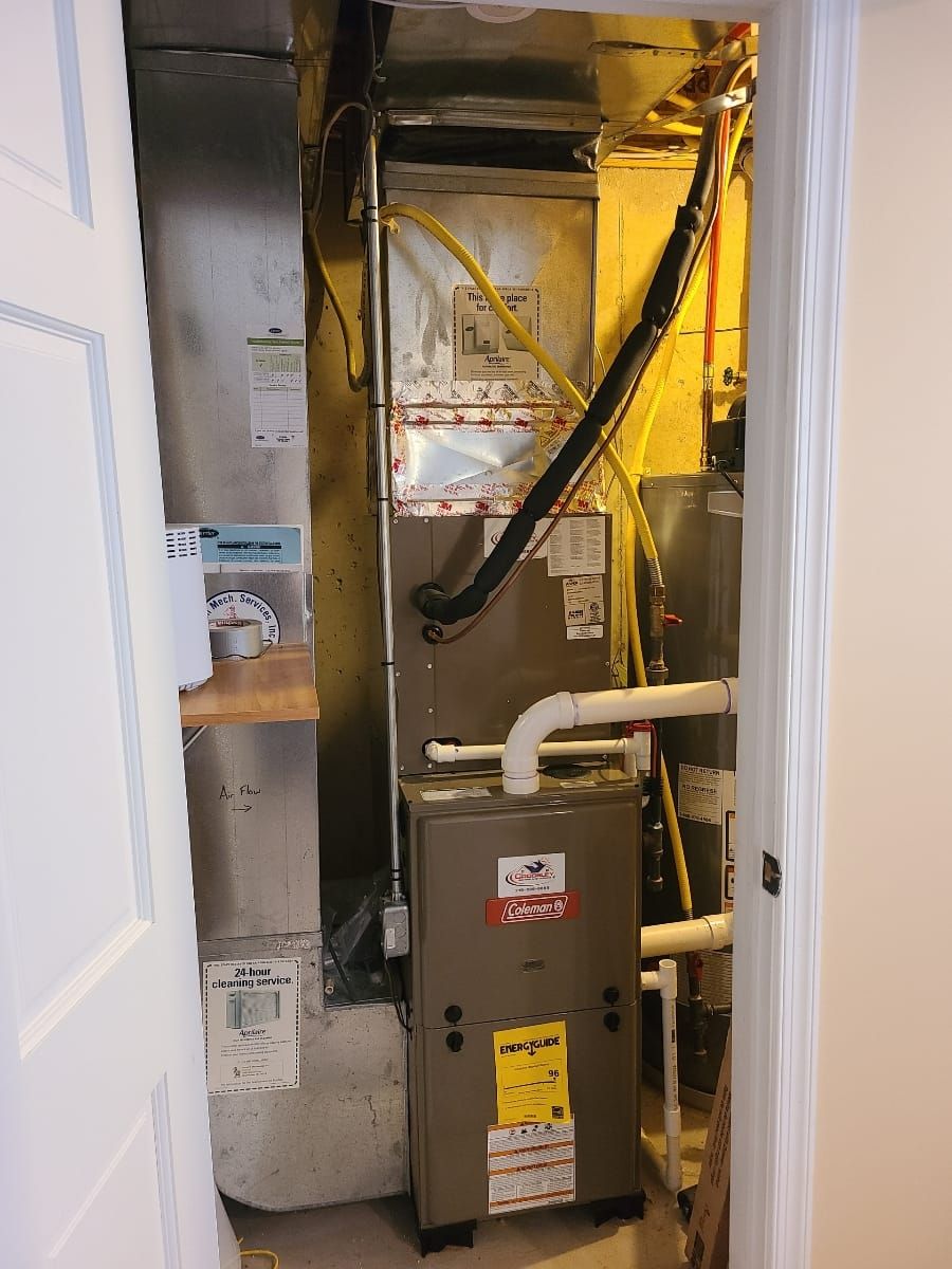 An air conditioner is sitting in a closet next to a door.