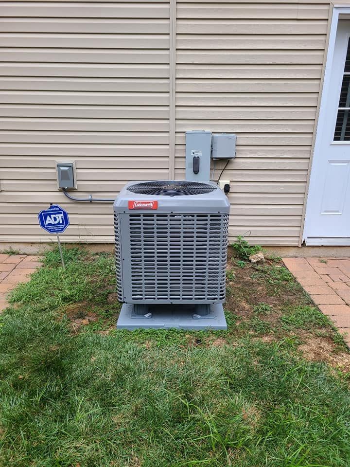 An air conditioner is sitting in the grass in front of a house.