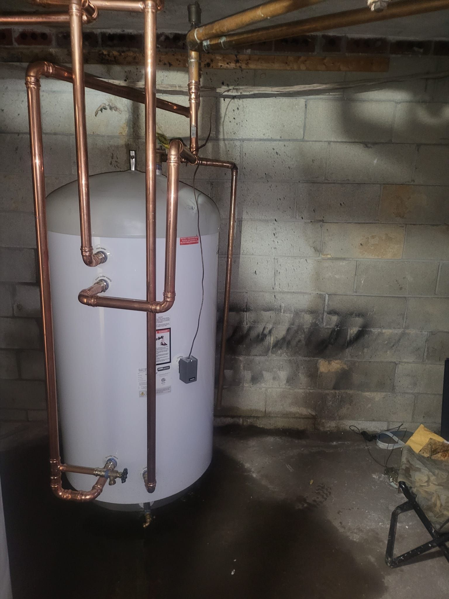 A white water heater with copper pipes attached to it