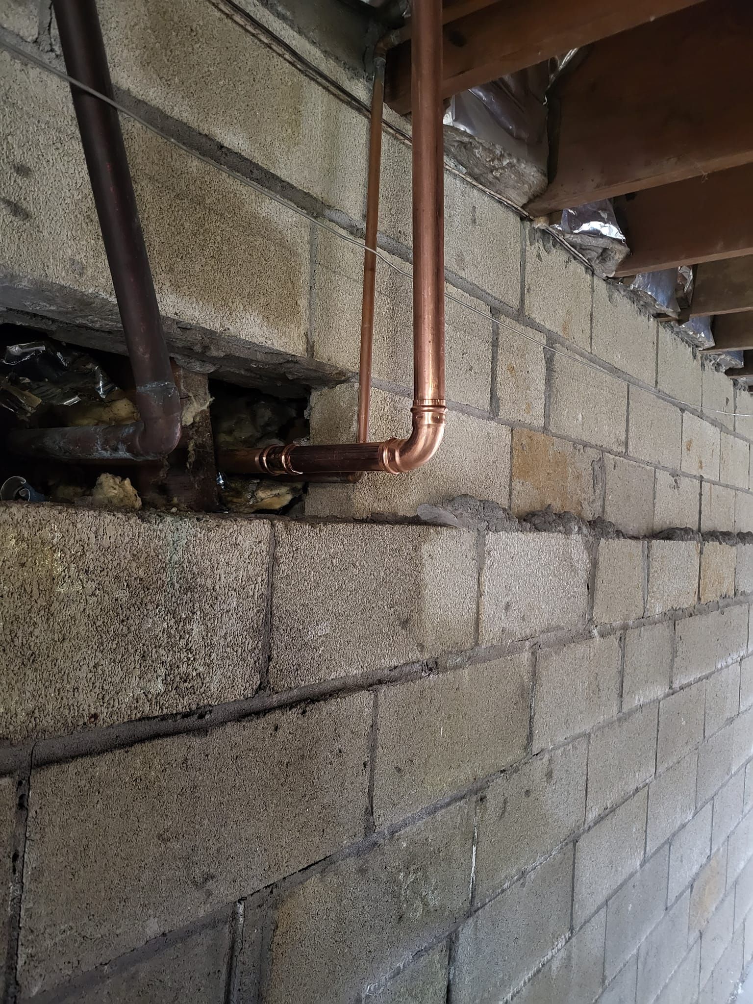 A copper pipe is connected to a brick wall.
