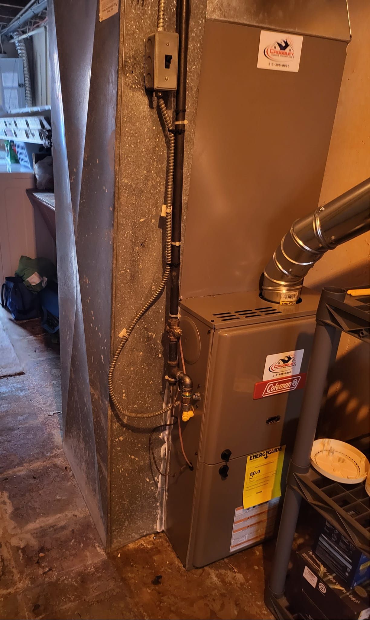A furnace is sitting in the corner of a room next to a wall.