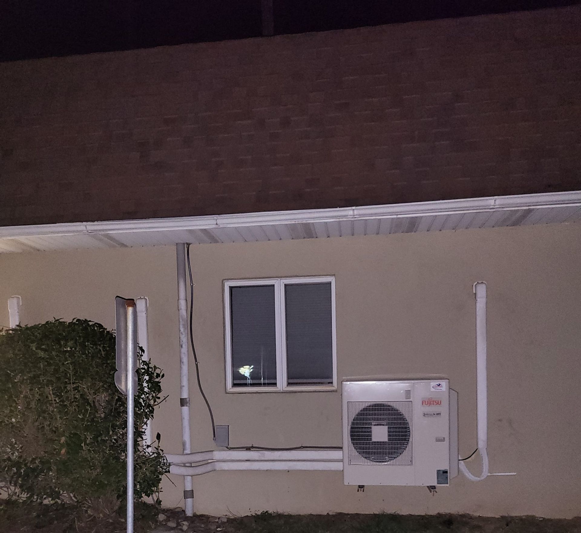 An air conditioner on the side of a house at night