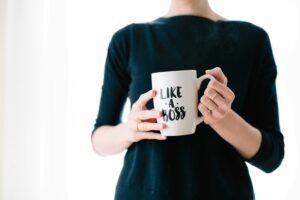 Person holding a white mug that says 
