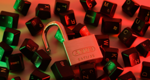 Open padlock surrounded by scattered black keyboard keys, lit by red and green lights.
