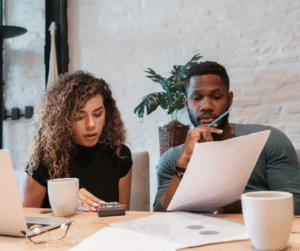 Woman with calculator and man with paper reviewing documents at a table.
