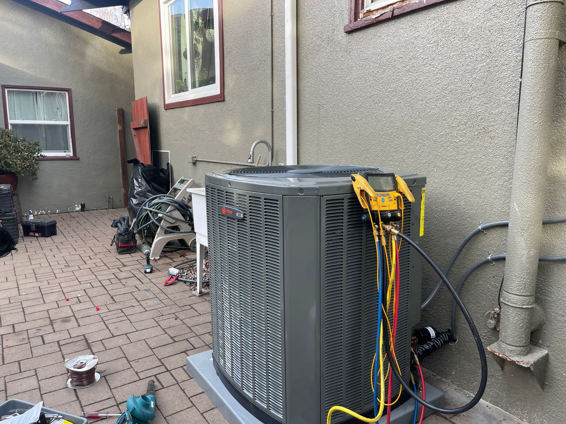 An air conditioner is being installed on the side of a house.