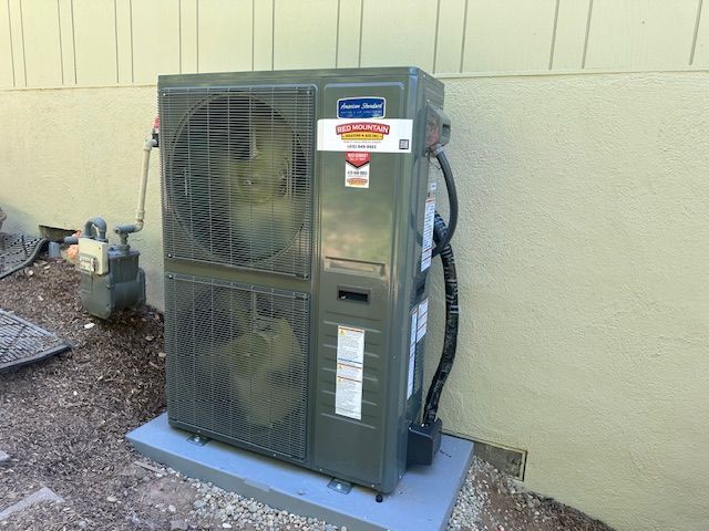 A large air conditioner is sitting outside of a building.