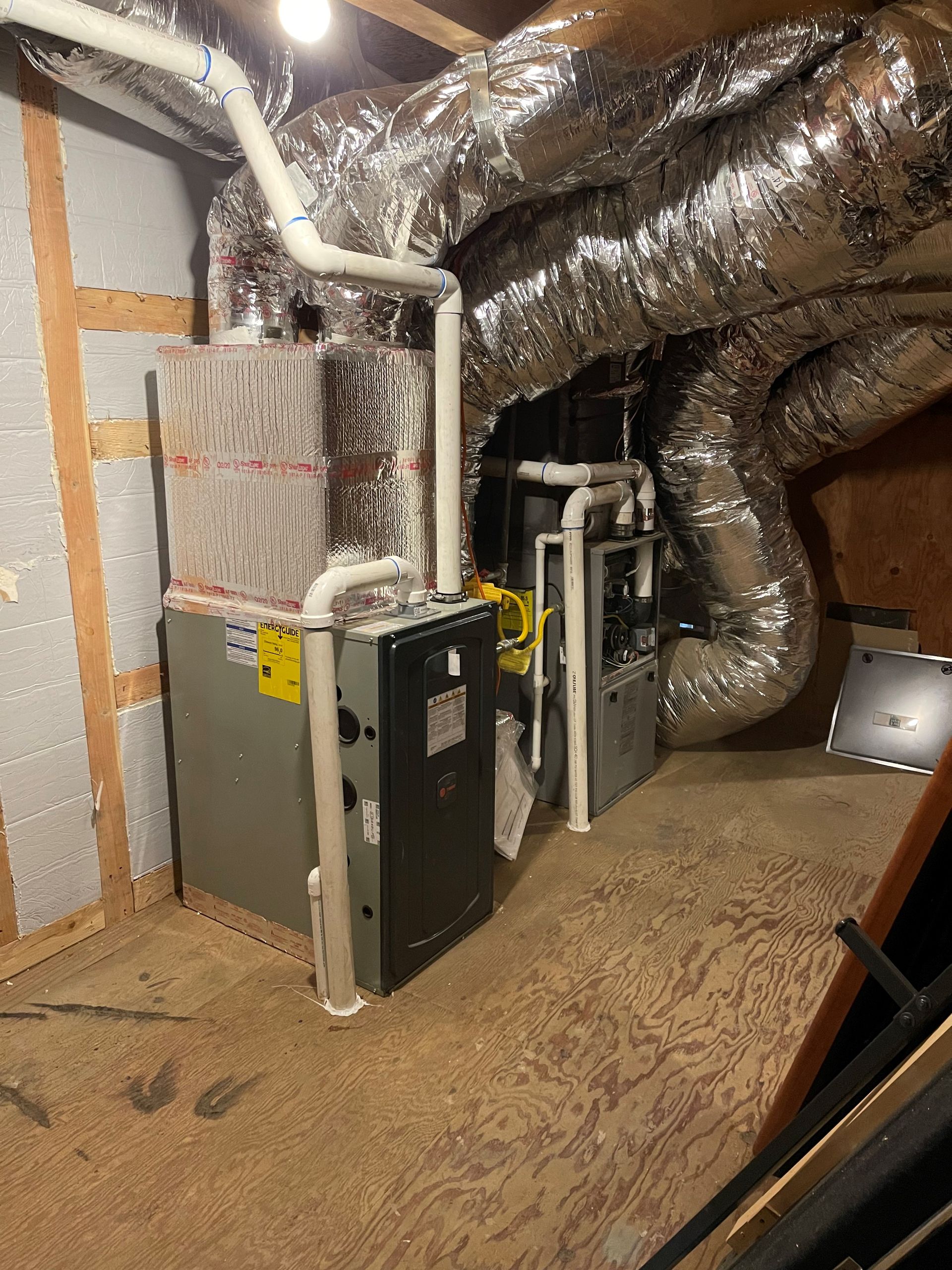 A room with a lot of pipes and a furnace in it.