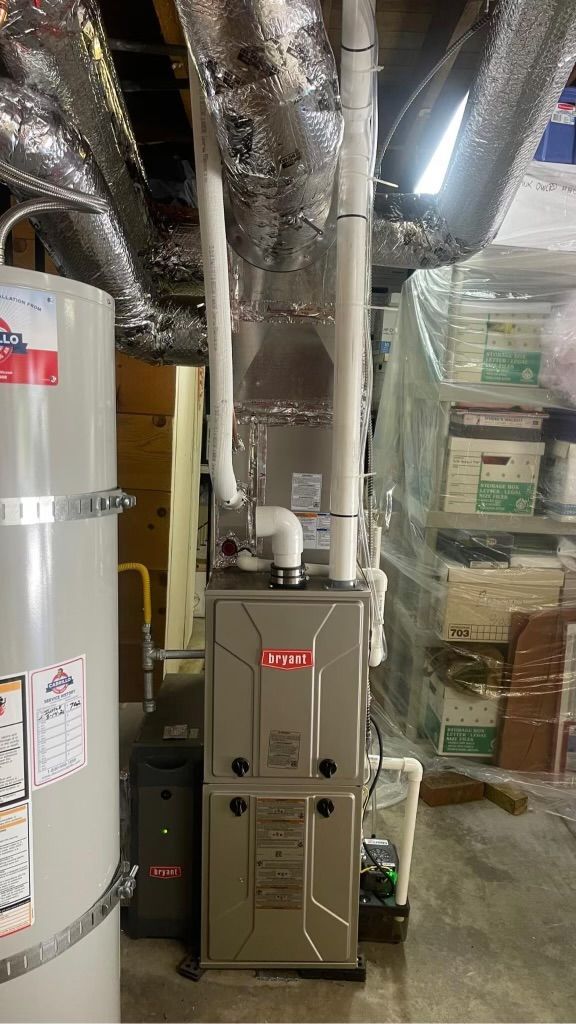A furnace is sitting in a basement next to a water heater.
