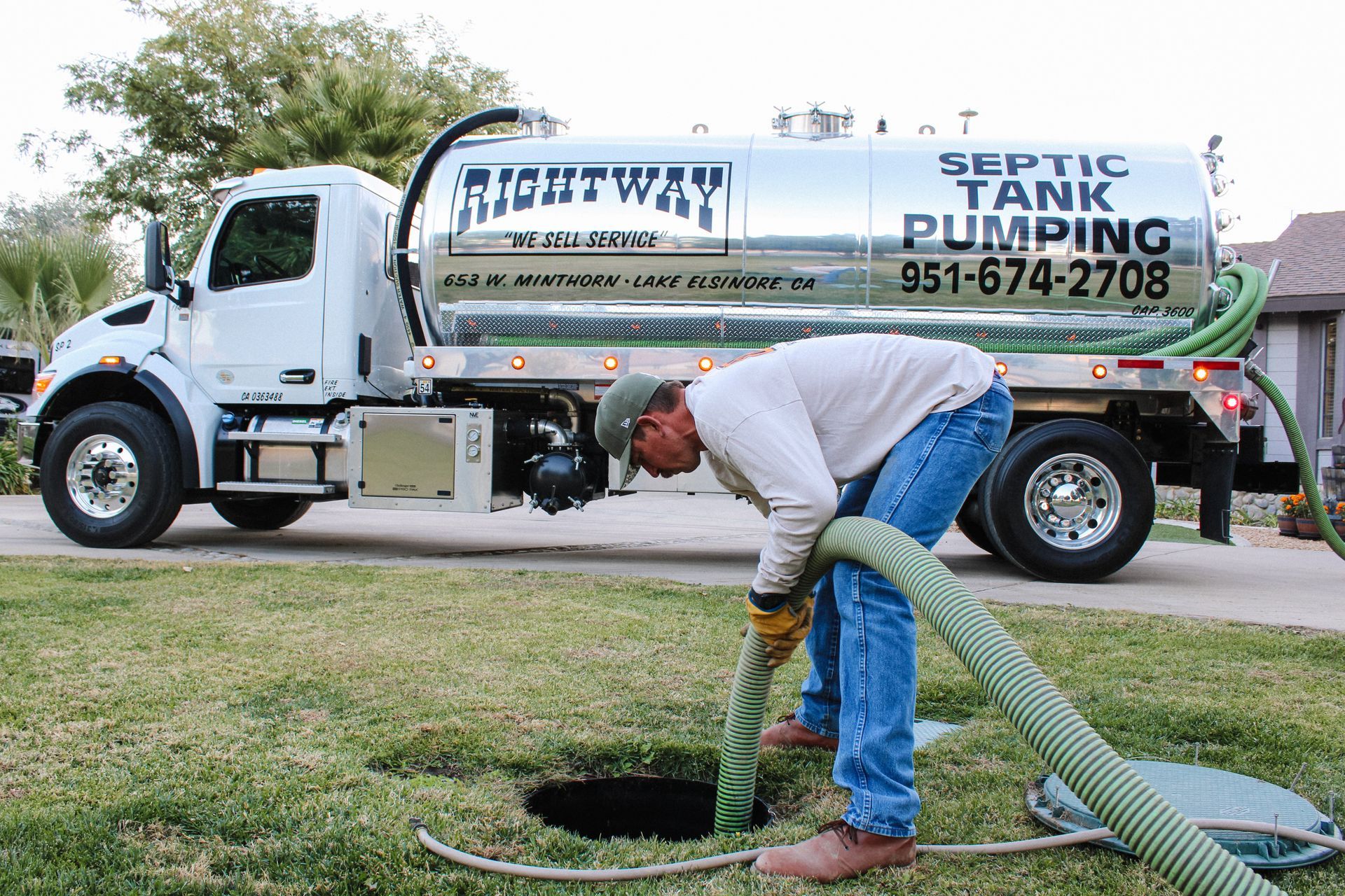 A septic tank is being pumped with a hose.