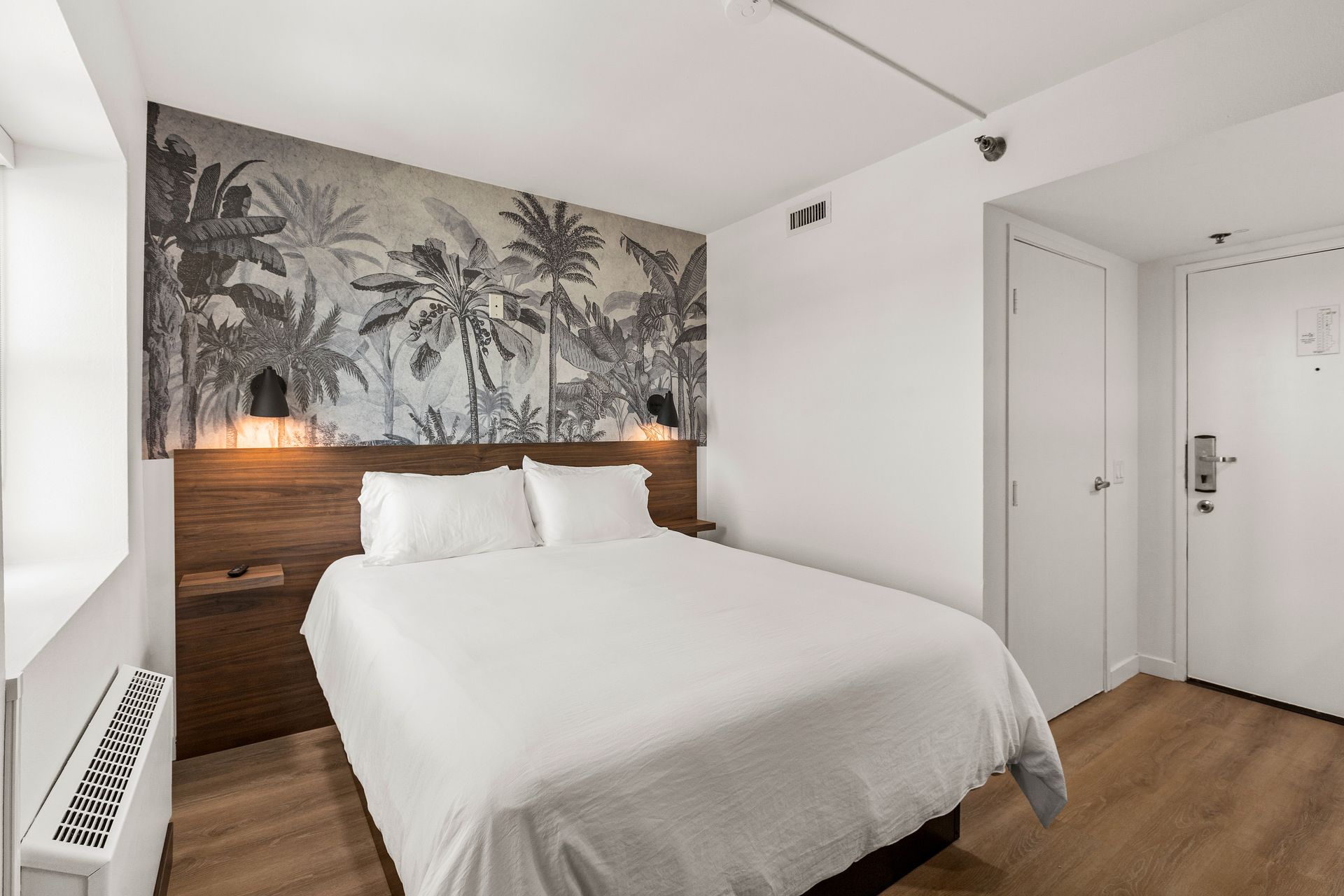 A hotel room with a king size bed and a mural on the wall.