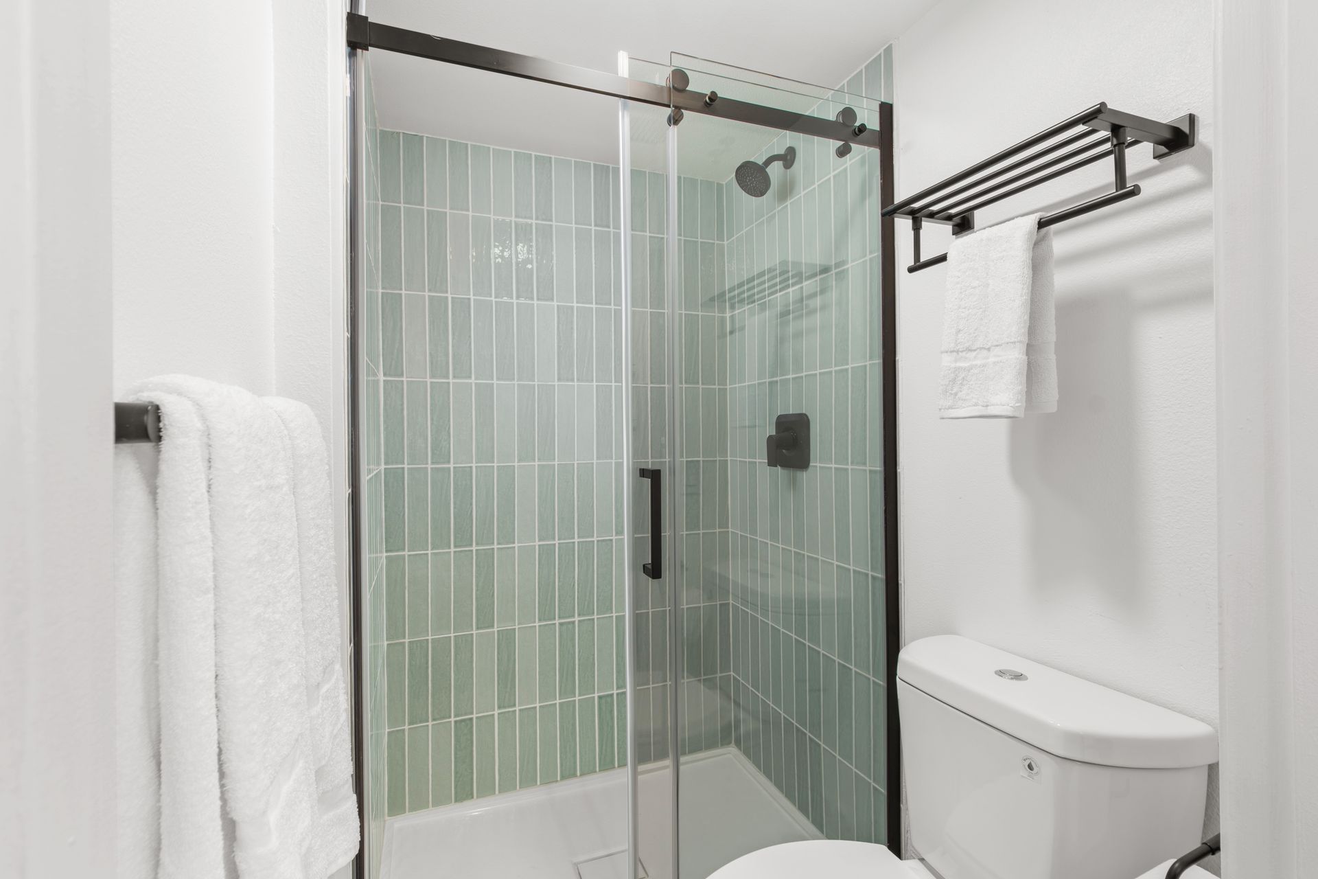 A bathroom with a toilet , shower , and towel rack.